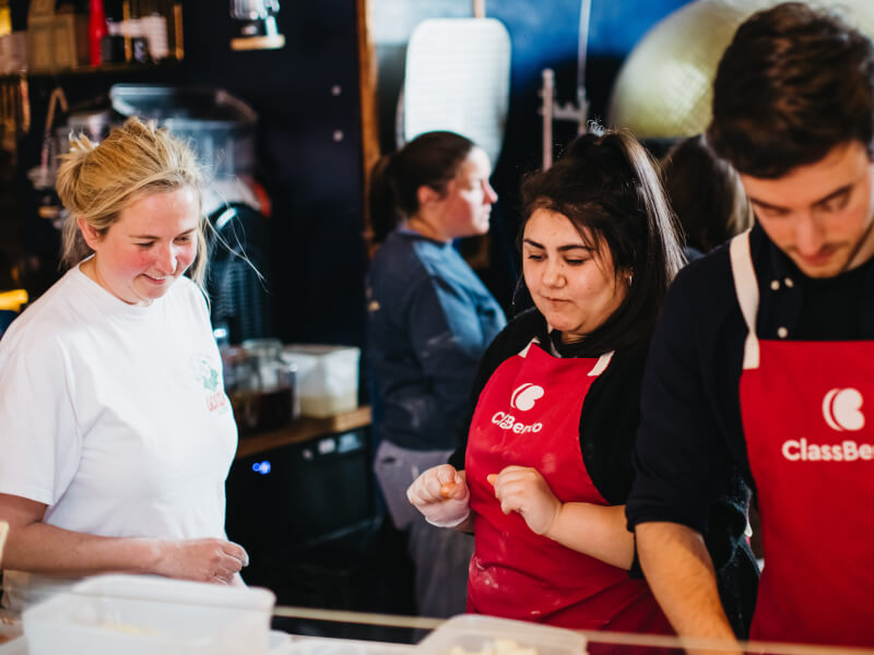 Two students are being shown how to cook by a teacher